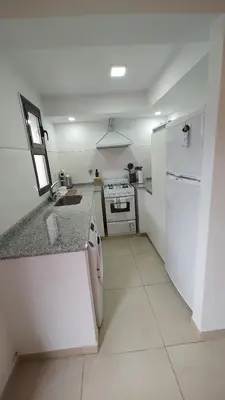 a white kitchen with a sink and a refrigerator at Duplex Zekkei in Villa General Belgrano