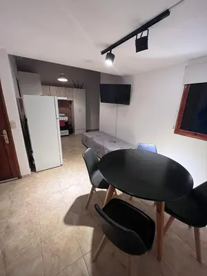 a room with a table and chairs and a kitchen at Departamento cerca del centro - Carhue in Villa Carlos Paz