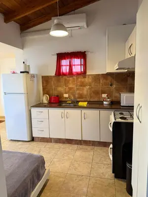 a kitchen with a white refrigerator and a red window at Departamento cerca del centro - Carhue in Villa Carlos Paz