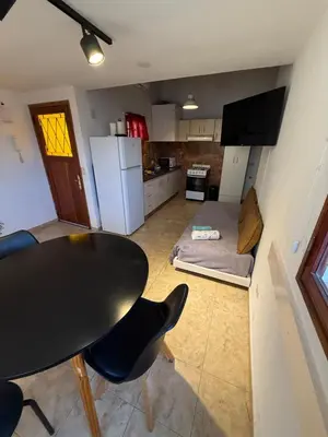 a kitchen with a table and two chairs and a table and a refrigerator at Departamento cerca del centro - Carhue in Villa Carlos Paz