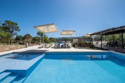a swimming pool with chairs and an umbrella over it at Complejo el Paine in Villa General Belgrano