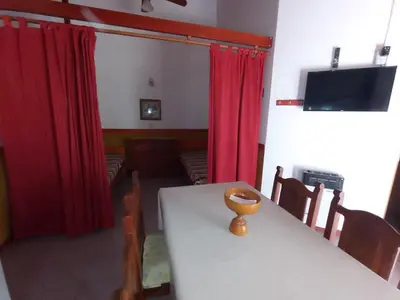 a dining room with a white table and red curtains at Cabañas Altos del Centro in Merlo