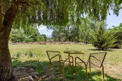 a table and chairs under a tree in a field at Habitación Suite Sami Llankay in Villa Ciudad Parque