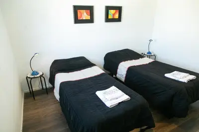 three beds in a room with black sheets at Bello Dpto, 20 minutos al Estadio Kempes, cerca de Quality, Hospital Privado in Cordoba