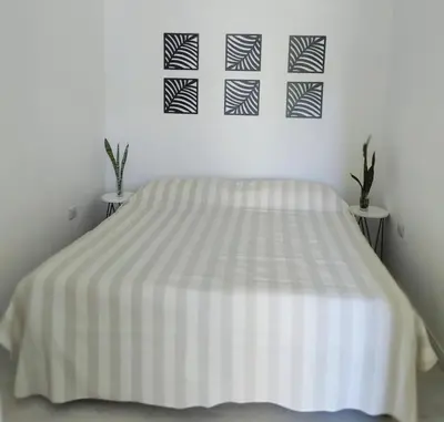 a white bedroom with a bed with a striped blanket at Bello Dpto, 20 minutos al Estadio Kempes, cerca de Quality, Hospital Privado in Cordoba
