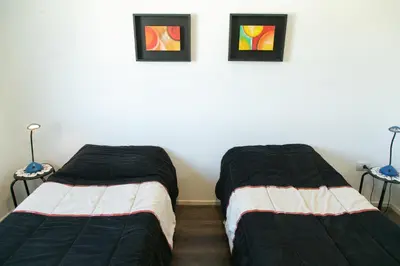 two beds in a room with two pictures on the wall at Bello Dpto, 20 minutos al Estadio Kempes, cerca de Quality, Hospital Privado in Cordoba
