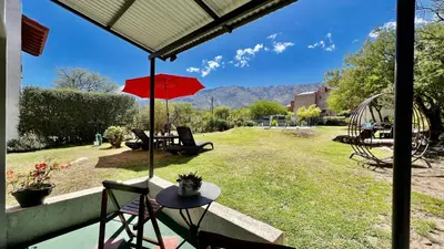 a patio with a table and an umbrella and a playground at Suite para dos con entrada independiente in Merlo