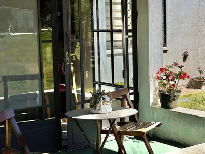a table and a chair on a porch with flowers at Suite para dos con entrada independiente in Merlo