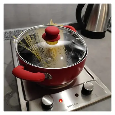 a red pot on a stove with spaghetti in it at CASA TRANSFORMER in Cordoba