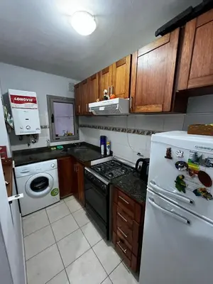 a kitchen with a white refrigerator and wooden cabinets at ALQUILO DEPTO AMUEBLADO 2 DORMITORIOS EN MICROCENTRO in Río Cuarto