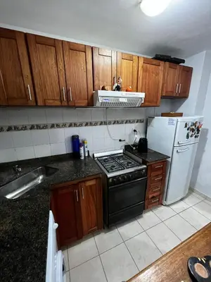 a kitchen with wooden cabinets and a stove and refrigerator at ALQUILO DEPTO AMUEBLADO 2 DORMITORIOS EN MICROCENTRO in Río Cuarto