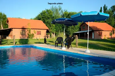two chairs and umbrellas next to a swimming pool at Yerba Buena casas de campo - Arroyo de los Patos in Nono