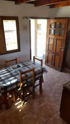 a dining room with a table and chairs and a door at POSADA LAS MARGARITAS in Santa Rosa de Calamuchita