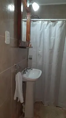a bathroom with a sink and a shower curtain at POSADA LAS MARGARITAS in Santa Rosa de Calamuchita