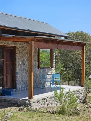 a house with a deck with a blue chair on it at Las Casitas de Piedra II in Villa General Belgrano