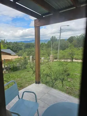 a porch with a table and chairs and a view of a field at Las Casitas de Piedra II in Villa General Belgrano