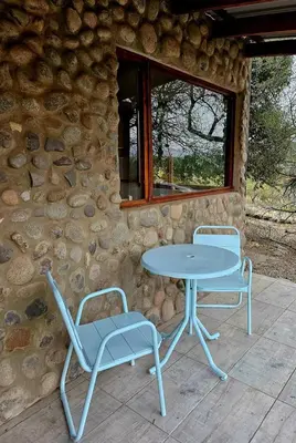a table and two chairs next to a stone building at Las Casitas de Piedra II in Villa General Belgrano