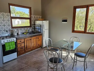 a kitchen with a table and chairs and a refrigerator at Las Casitas de Piedra II in Villa General Belgrano