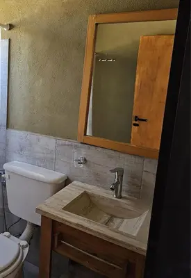 a bathroom with a sink and a toilet and a mirror at Las Casitas de Piedra II in Villa General Belgrano