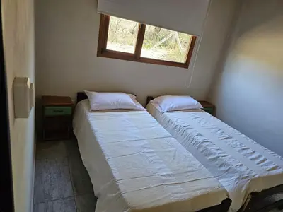 two beds in a small room with a window at Las Casitas de Piedra II in Villa General Belgrano