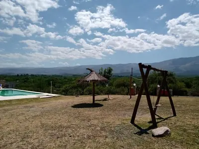 a playground with an umbrella and a swimming pool at Cabañas Colibri in Las Rabonas