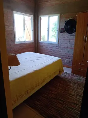 a bedroom with a bed and two windows at Cabañas Colibri in Las Rabonas