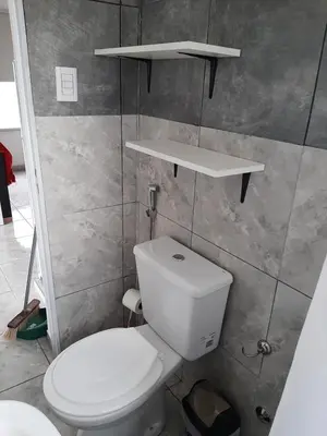 a bathroom with a toilet and shelves on the wall at Cabañas Colibri in Las Rabonas
