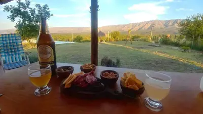 a bottle of beer and two glasses of food on a table at Cabañas Colibri in Las Rabonas