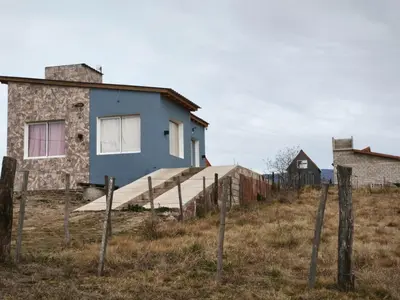 a blue house in a field with a fence at Altura serrana in Villa Yacanto