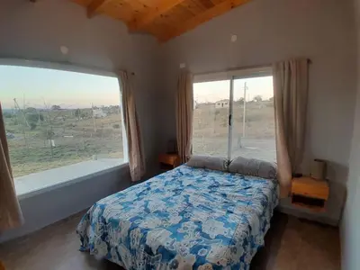 a bedroom with a bed and a large window at Altura serrana in Villa Yacanto