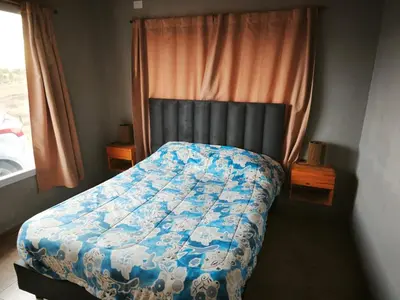 a bedroom with a bed with a blue comforter and a window at Altura serrana in Villa Yacanto