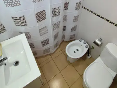 a white bathroom with a toilet and a sink at Casa Nuup in Río Tercero