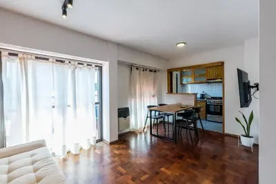 a living room with a table and a kitchen at Departamento con balcón espectacular by Lofty in Cordoba