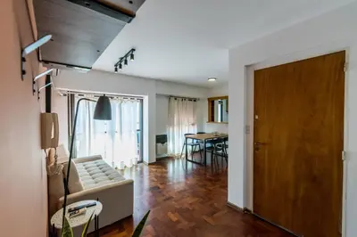 a living room with a couch and a wooden door at Departamento con balcón espectacular by Lofty in Cordoba