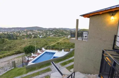 a house with a swimming pool next to a building at Complejo Lamarca in Villa Carlos Paz