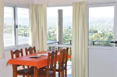 a dining room with a table and chairs and windows at Complejo Lamarca in Villa Carlos Paz