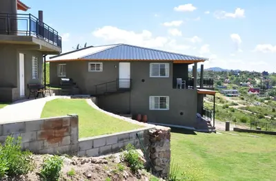 a house on top of a hill with a yard at Complejo Lamarca in Villa Carlos Paz