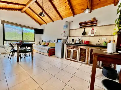 a kitchen and living room with a table and a couch at Departamento con vista a las sierras en Planta Alta para 2 a 4 personas in Merlo
