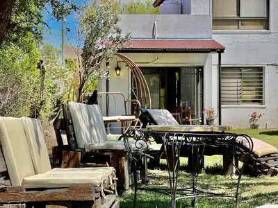 a group of chairs and a table in front of a house at Departamento con vista a las sierras en Planta Alta para 2 a 4 personas in Merlo