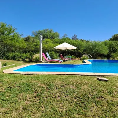 a swimming pool with an umbrella and chairs in a yard at Vayu- en La Casa de Nanda in San Javier