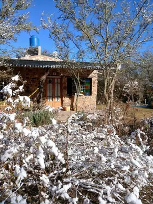 a log cabin in the snow in front of a house at Vayu- en La Casa de Nanda in San Javier