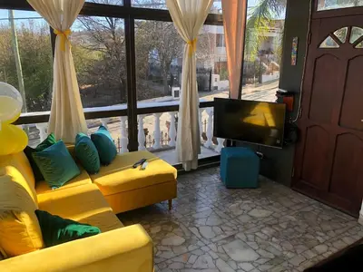 a living room with a yellow couch and a tv at Casa Maravilla in Villa Carlos Paz