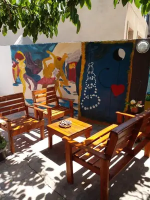 a group of wooden benches in front of a mural at Casa Maravilla in Villa Carlos Paz