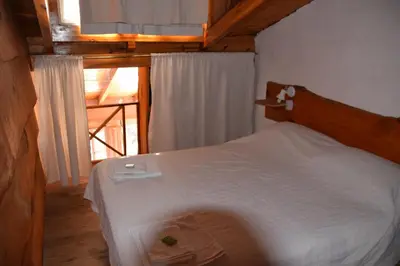 a bedroom with a white bed with a wooden headboard at Complejo El Alto in Tanti