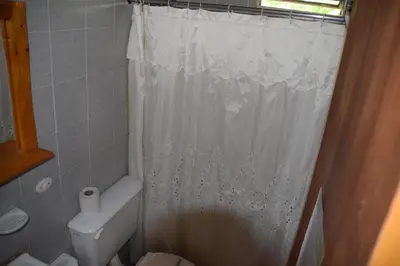 a bathroom with a white shower curtain and a toilet at Complejo El Alto in Tanti