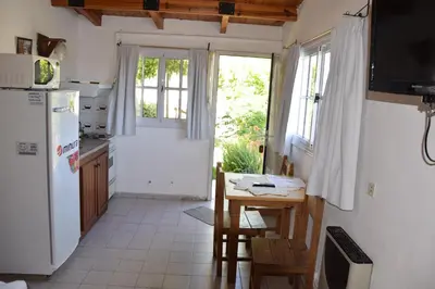 a kitchen with a table and a refrigerator at Complejo El Alto in Tanti