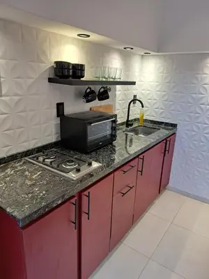 a kitchen with red cabinets and a stove and a sink at Moderno Departamento B° Urca P/ 4 Personas in Cordoba