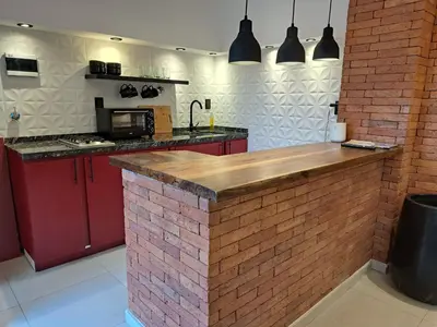 a kitchen with red cabinets and a brick wall at Moderno Departamento B° Urca P/ 4 Personas in Cordoba