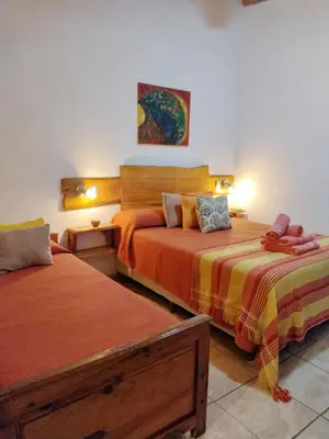 a bedroom with two beds with orange sheets at Del Sol a la Montaña EcoLodge - Turismo Consciente in Potrero de Garay