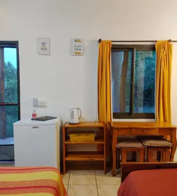 a room with two beds and a window with yellow curtains at Del Sol a la Montaña EcoLodge - Turismo Consciente in Potrero de Garay